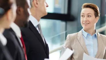 Grupo de profesionales en una reunión de trabajo sonríen y conversan.