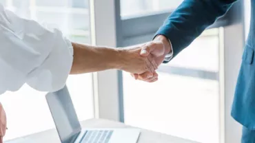 Dos personas dando la mano en una oficina.