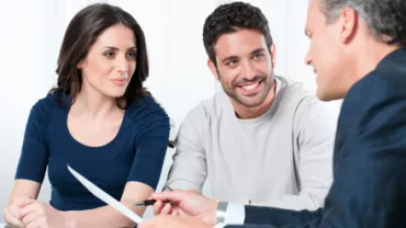 Grupo de personas en una reunión de trabajo, sonriendo y conversando.